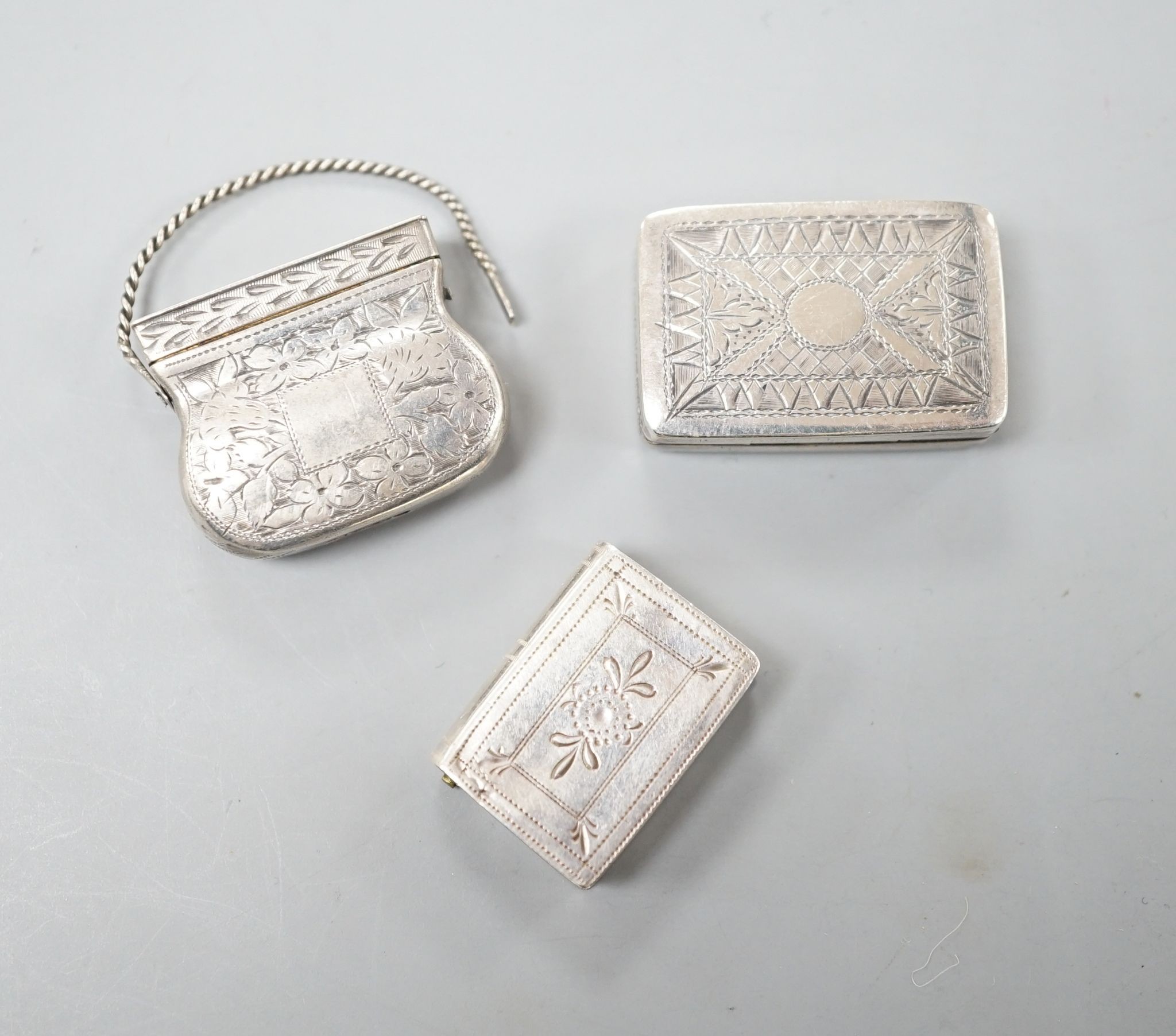 A George IV novelty silver vinaigrette, modelled as a handbag, Gervase Wheeler, Birmingham, 1832, 27mm(handle at one end detached), one other silver vinaigrette, Edward Smith, Birmingham, 1829 and a similar silver 'book'